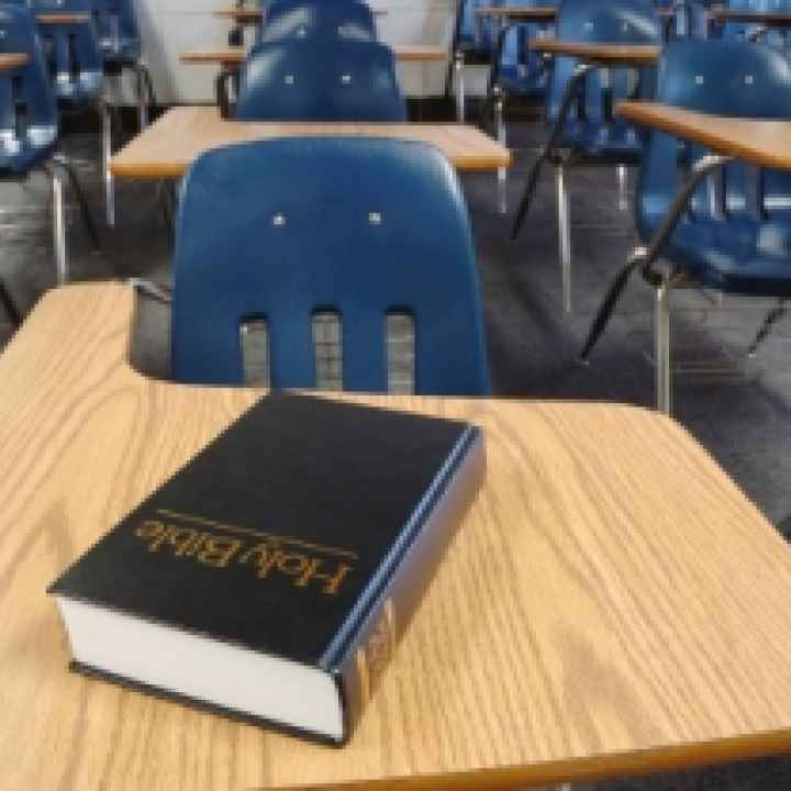 a classroom full of desks and chairs with a holy bible on one desk