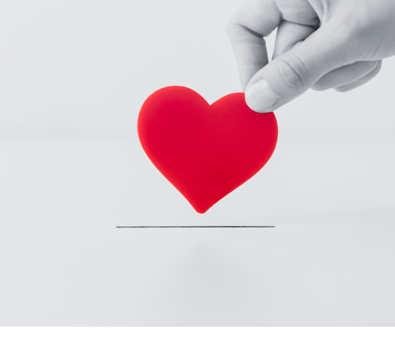 Black and white image of hand grabbing a red heart